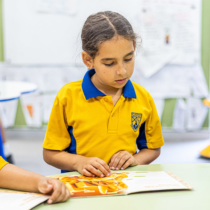 Student reading a book in the library at St Andrews Primary School Marayong